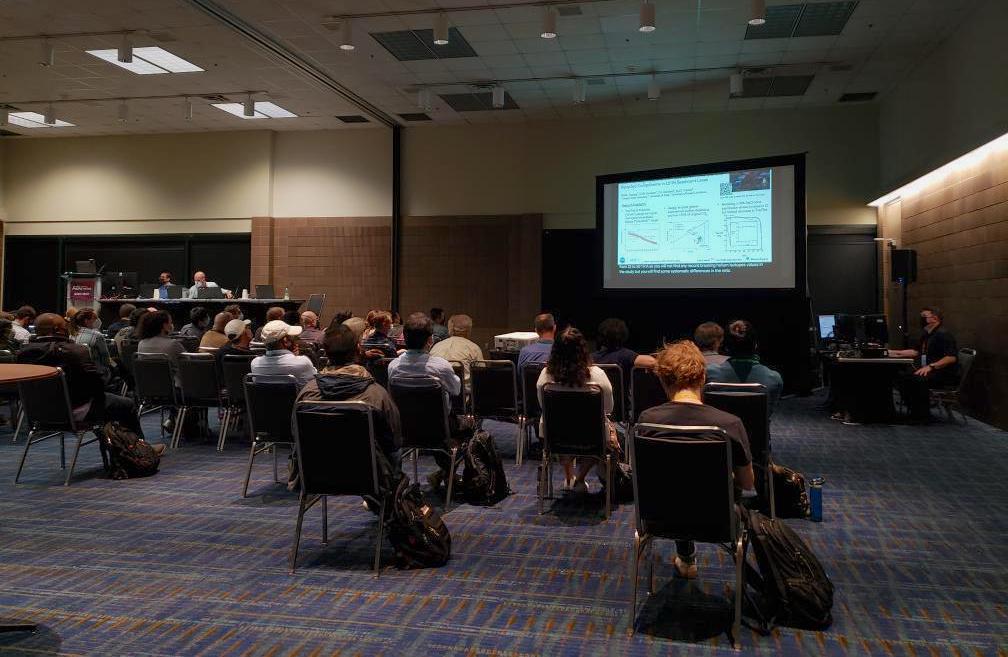 View of back of AGU presentation room during Thi's live remote presentation. About 2 dozen conference attendees are watching. The chairs appear to be spaced apart for social distancing.